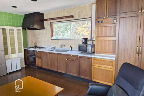 Una cocina con armarios de madera y un fregadero y una ventana. en ist villa 06 Private Beachfront Sleeps 16, en Wada