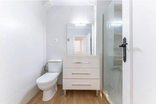 a white bathroom with a toilet and a glass shower at Apartamento en 1ª línea de playa con parking privado in El Campello