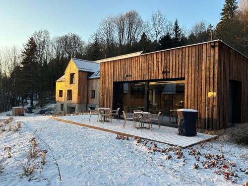 a wooden building with tables and chairs in the snow at Apartmány Hraničná s privátním wellness in Bedřichov