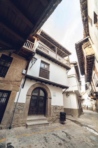 a white building with a door and a balcony at Casa Rural "Calle Real" en La Vera in Villanueva de la Vera