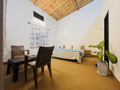 a bedroom with a bed and a chair and a plant at Ekatma Stays - Farm & Homestay, Kakrighat in Shitlakhet