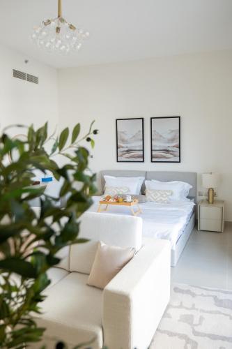 a white bedroom with a bed and a couch at Elegant Studio apartment in Yas Golf collection with Balcony and Free parking l Near Yas water world & Ferrari World & Warner brothers in Abu Dhabi