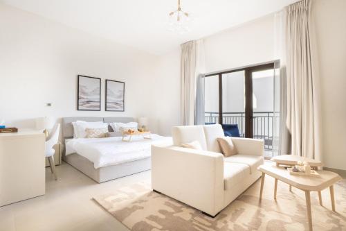 a white living room with a bed and a couch at Elegant Studio apartment in Yas Golf collection with Balcony and Free parking l Near Yas water world & Ferrari World & Warner brothers in Abu Dhabi