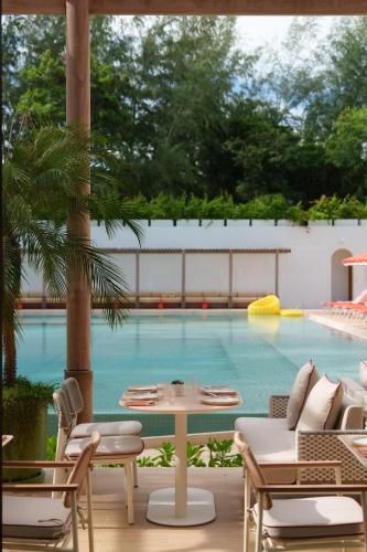 a pool with a table and chairs in front of it at The Standard, Pattaya Na Jomtien in Na Jomtien