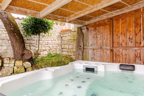 a bath tub filled with water next to a tree at L'Atelier du Clos avec Jacuzzi in Puilboreau