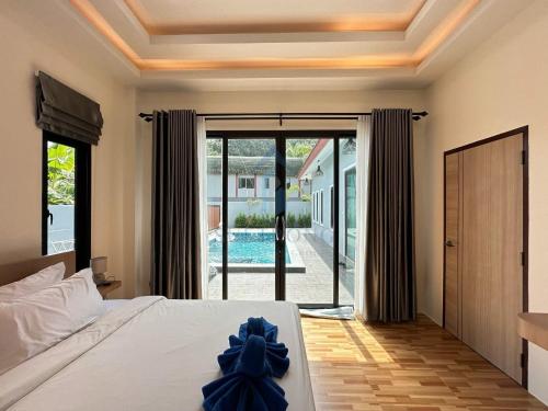 a bedroom with a bed and a sliding glass door at LOMA Pool Villa in Ban Nong Thale