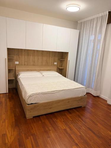 a bedroom with a bed with white cabinets and wood floors at Casa da Luigina 2 in Chioggia