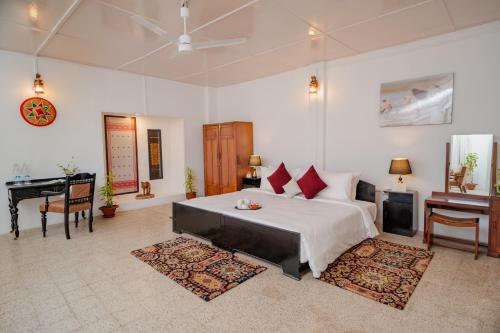 a bedroom with a bed and a desk and a piano at amã Stays & Trails - Diffloo Bungalow, Assam in Bokākhāt