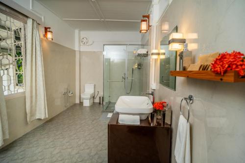 a bathroom with a toilet and a shower and a sink at amã Stays & Trails - Diffloo Bungalow, Assam in Bokākhāt