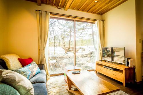 a living room with a couch and a large window at Misorano Chalet in Hakuba