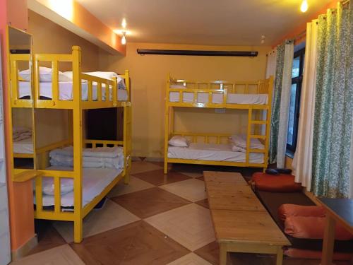 Habitación con 3 literas y mesa. en Dreamcatcher Homestay, en McLeod Ganj