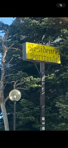 a yellow street sign on a pole next to a tree at Relax House in Roccaraso