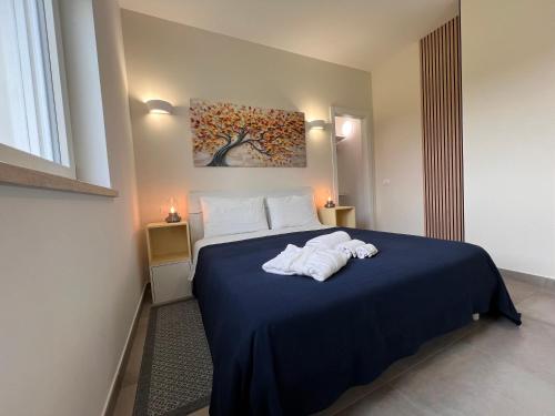 a bedroom with a blue bed with towels on it at Guest House Montestallone in Formello