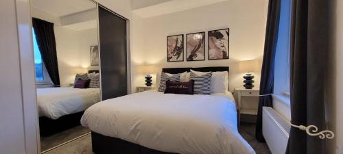 een slaapkamer met twee bedden en een grote spiegel bij Eccles Apartment in Stirling