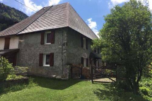 una casa di pietra con un albero di fronte di Charmante maison familiale a Saint-Pierre-de-Chartreuse