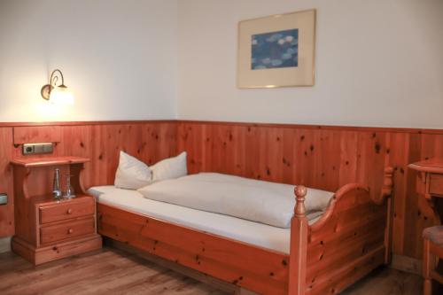 a bedroom with a bed with a wooden wall at Brauereigasthof Gut Forsting in Pfaffing