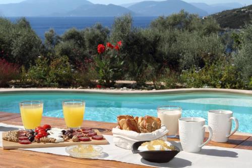una mesa con desayuno y bebidas junto a una piscina en Villa Agapi Spacious Stone Retreat with Jacuzzi and Private Pool, en Sivota