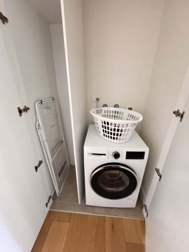 a laundry room with a washing machine and a basket on it at 1Br City View apt near SthnCrs Wifi Pool Gym in Melbourne