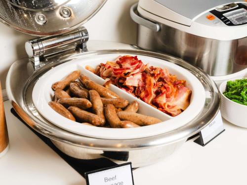 Un plato de comida con salchichas y pizza en un mostrador. en Mercure Brisbane Garden City, en Brisbane