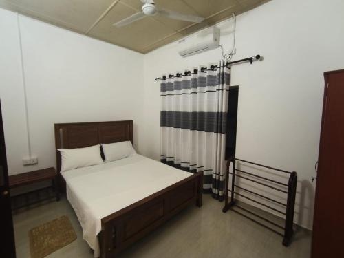 ein kleines Schlafzimmer mit einem Bett und einem Vorhang in der Unterkunft Villa Rest Haven in Galle