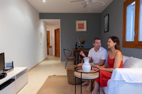 a man and woman sitting on a couch in a living room at APARTAMENTO EL ROJO in Can Picafort