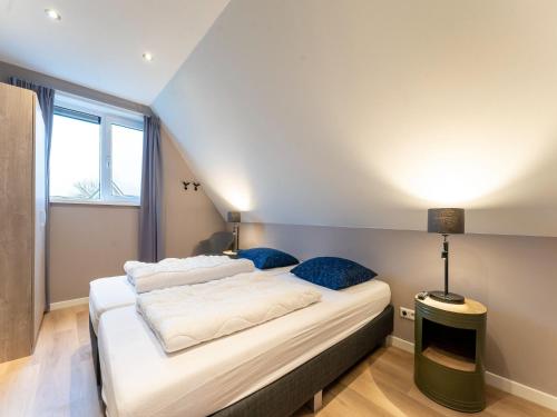 a bedroom with a large white bed with blue pillows at Serene Holiday Home in De Koog Texel with Sauna in Westermient