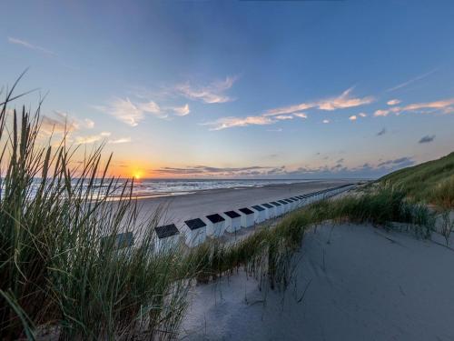 a row of chairs on a beach at sunset at Serene Holiday Home in De Koog Texel with Sauna in Westermient