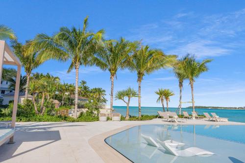 a resort swimming pool with palm trees and the ocean at Beachfront 3 bedroom Luxury Residence in Nassau