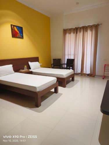 two beds in a room with yellow walls at Abhushan Mahal in Nīmri