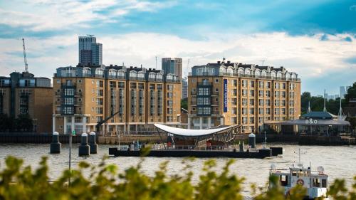 a boat in the water in front of some buildings at a&o London Docklands Riverside in London