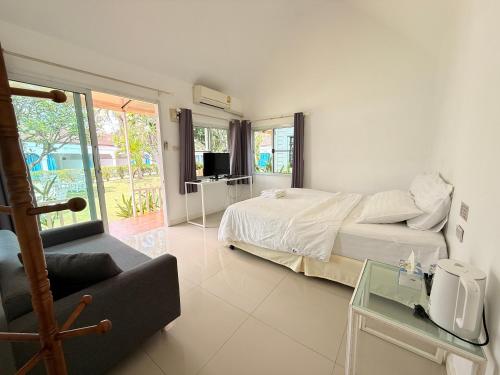 ein Schlafzimmer mit einem Bett und einer Couch und einem Fernseher in der Unterkunft Pophouse in Phetchaburi
