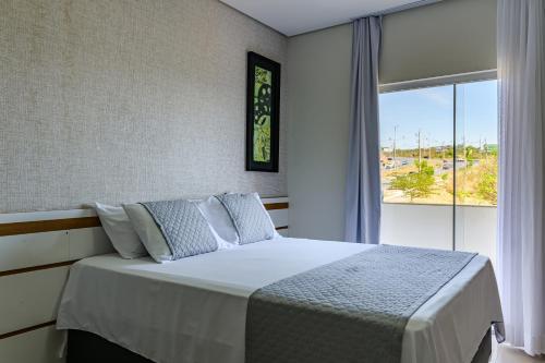 a bedroom with a bed and a large window at OYO Tropical Confort Hotel, Brasilia in Brasília