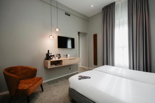 a hotel room with a bed and a chair and a tv at Leerhotel Het Klooster in Amersfoort