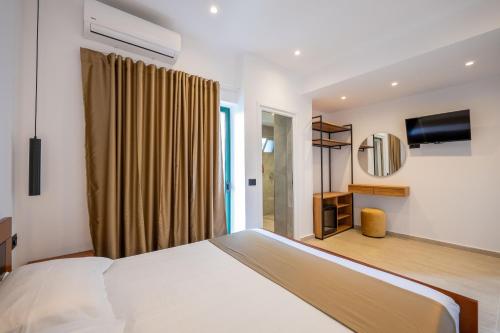 ein Schlafzimmer mit einem weißen Bett und einem Fernseher in der Unterkunft Hotel ENAD in Ksamil