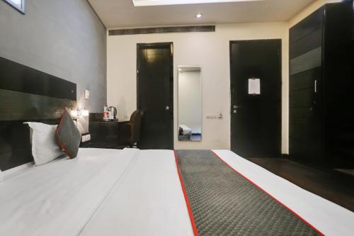 Un dormitorio con una gran cama blanca y puertas negras. en Collection O Cambridge, en Dhankot