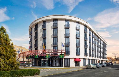 a large white building with cars parked in front of it at Exe Doña Carlota in Ciudad Real