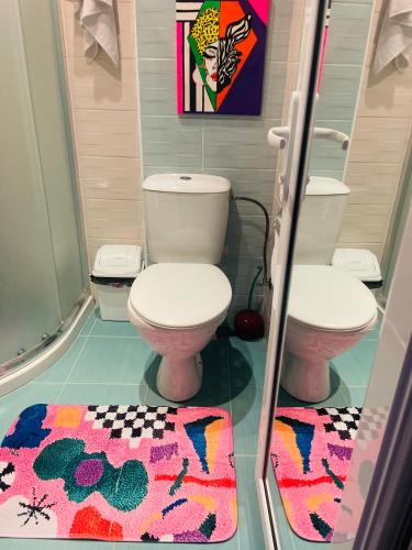 a bathroom with a toilet and two rugs at ADMIRAL PLASA studiyo-25C in Sunny Beach