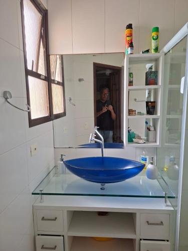 Ein Mann, der ein Foto von einem blauen Waschbecken in einem Badezimmer macht in der Unterkunft Apartamento Enseada in Guarujá