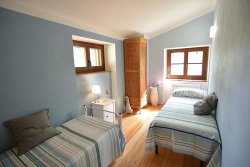 two beds in a room with blue walls and wooden floors at Historic Farmhouse In The Tuscan Hills in Caprese Michelangelo