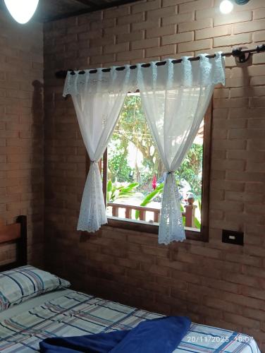 a bedroom with a window with a white curtain at Pousada Mar Azul in Trindade