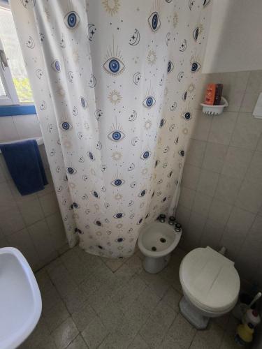 a bathroom with a toilet and a shower curtain at Casita funcional en Claromeco in Balneario Claromecó