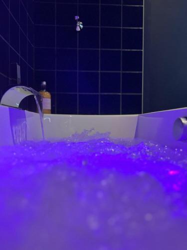 eine Badewanne mit violetter Beleuchtung im Bad in der Unterkunft Les Couleurs du Lac in Gérardmer