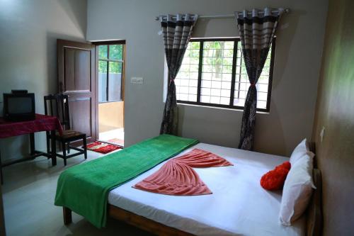 a bedroom with a bed with red and green sheets at Dean Dale Cottages in Thekkady