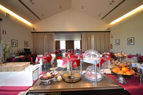 a restaurant with tables and chairs with food on a buffet at Casalgrande Hotel in Salvaterra