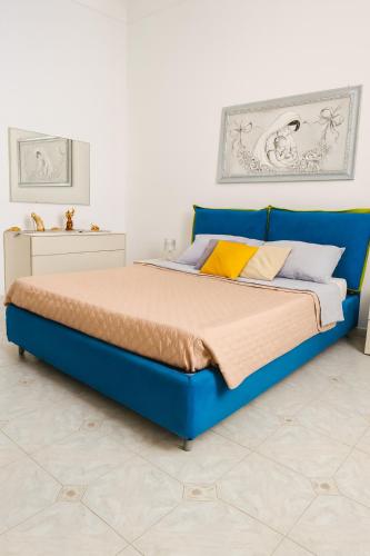 a bed in a room with blue and yellow pillows at A un passo dal cuore in Mesagne