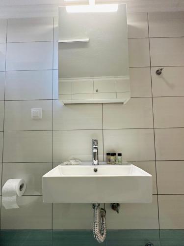 a white sink in a white tiled bathroom at ESTIA Apollon in Drama