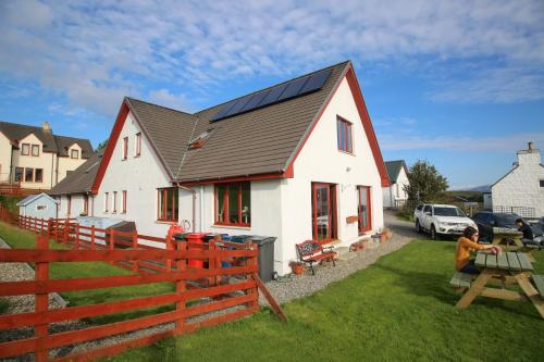 a man sitting in front of a house with solar panels at Arle Lodge in Tobermory