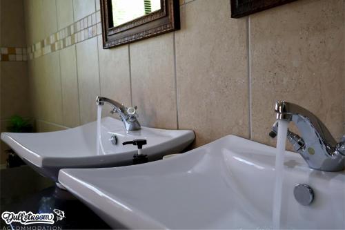 een badkamer met 2 witte wastafels en een spiegel bij Central Park in Dullstroom