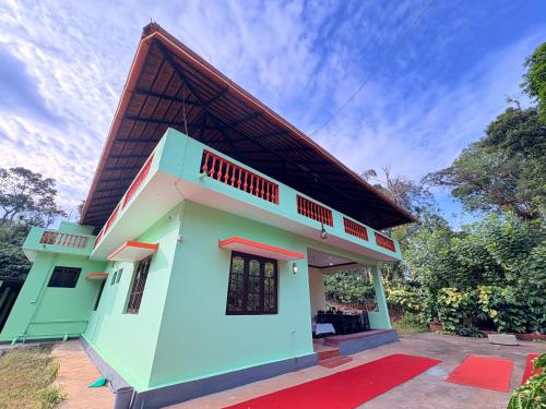 a green house with a brown roof at KOORGI RETREAT- Coorg in Napoklu
