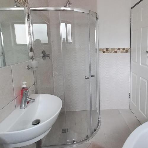 a bathroom with a shower and a white sink at 200 on Genazzano in Densainagar